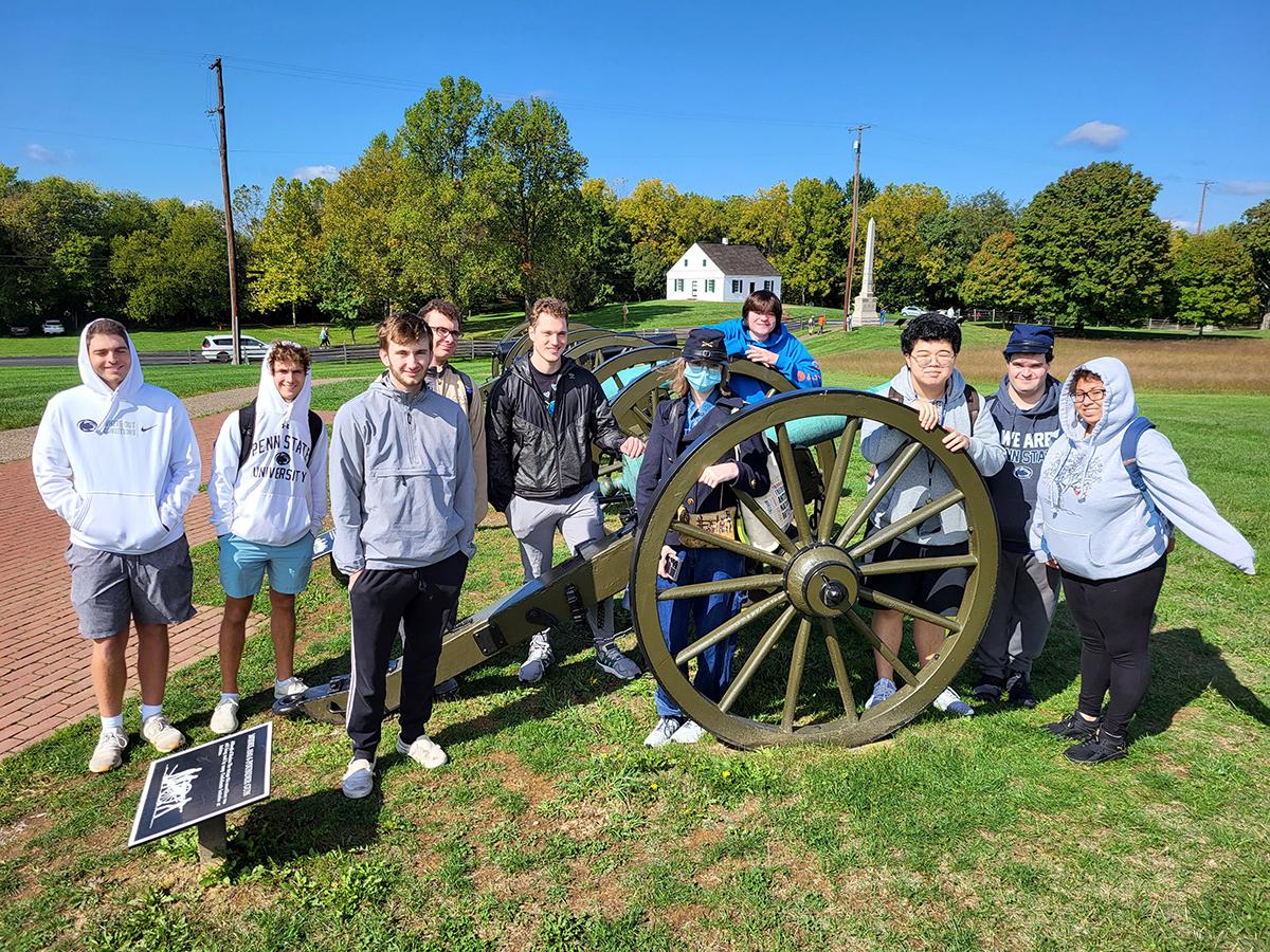 Penn State Altoona history students pose for a photo around a cannon at the Antietam battleground site