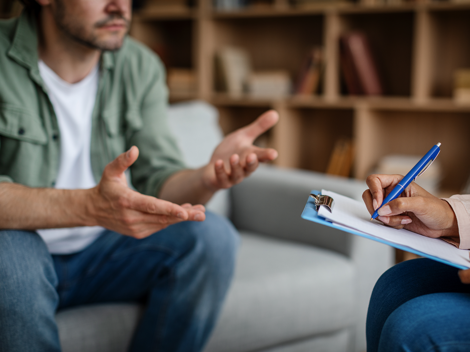 Person sitting on couch talking to a therapist who is taking notes