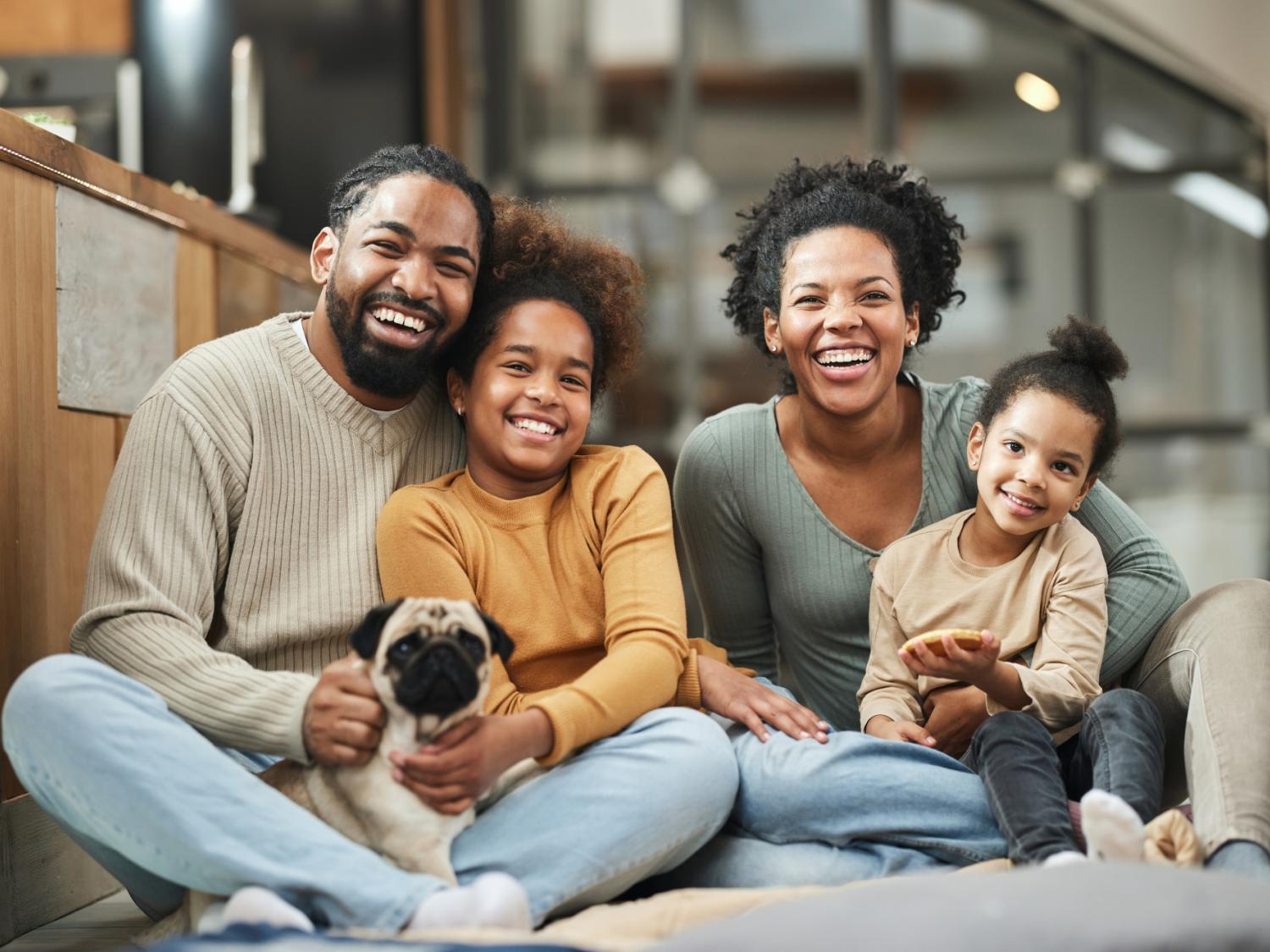 Happy parents with their children and a dog spending time at home.