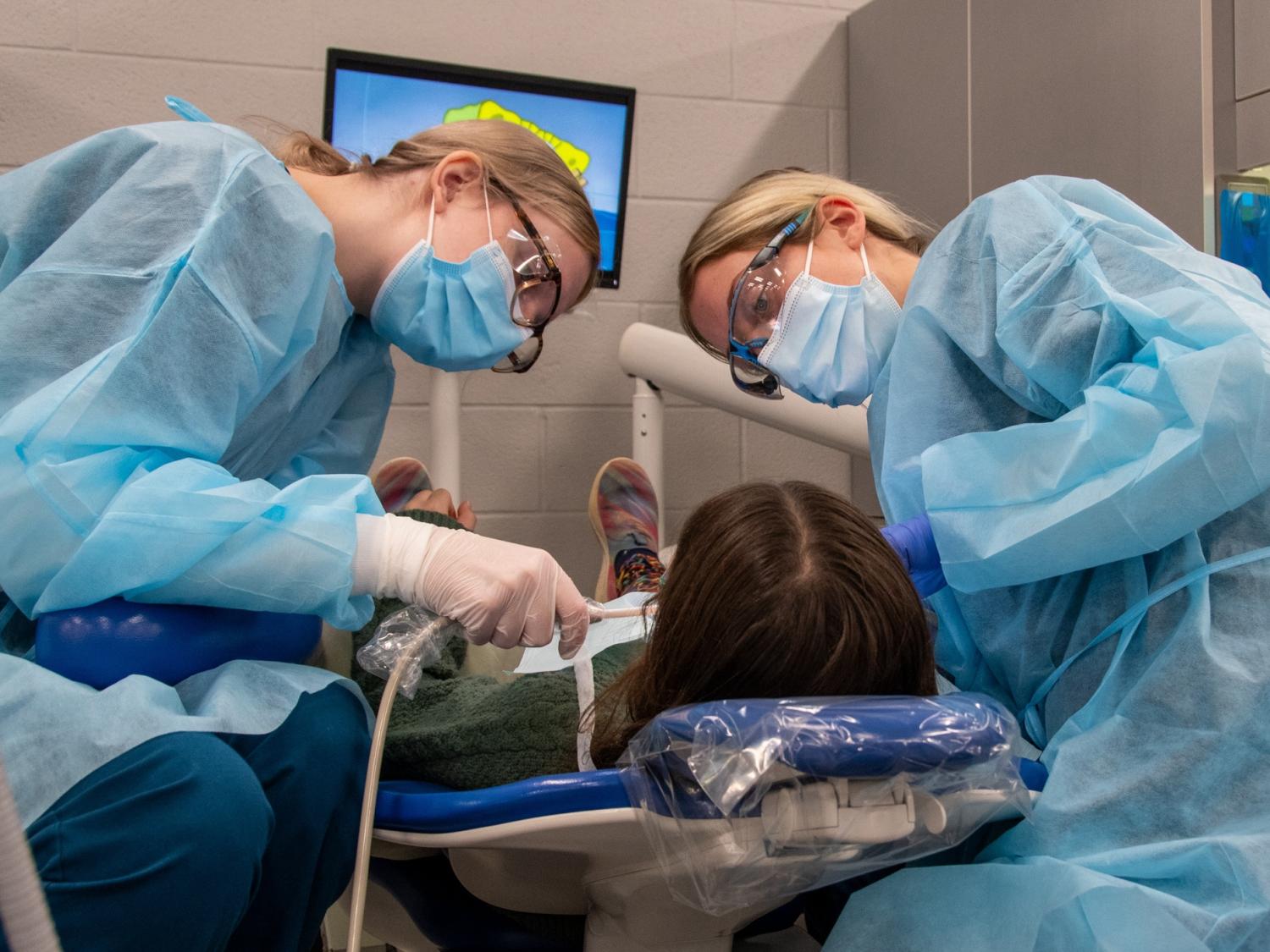Two Penn College dental hygiene students examine a child's teeth during the 2023 Sealant Saturday event.
