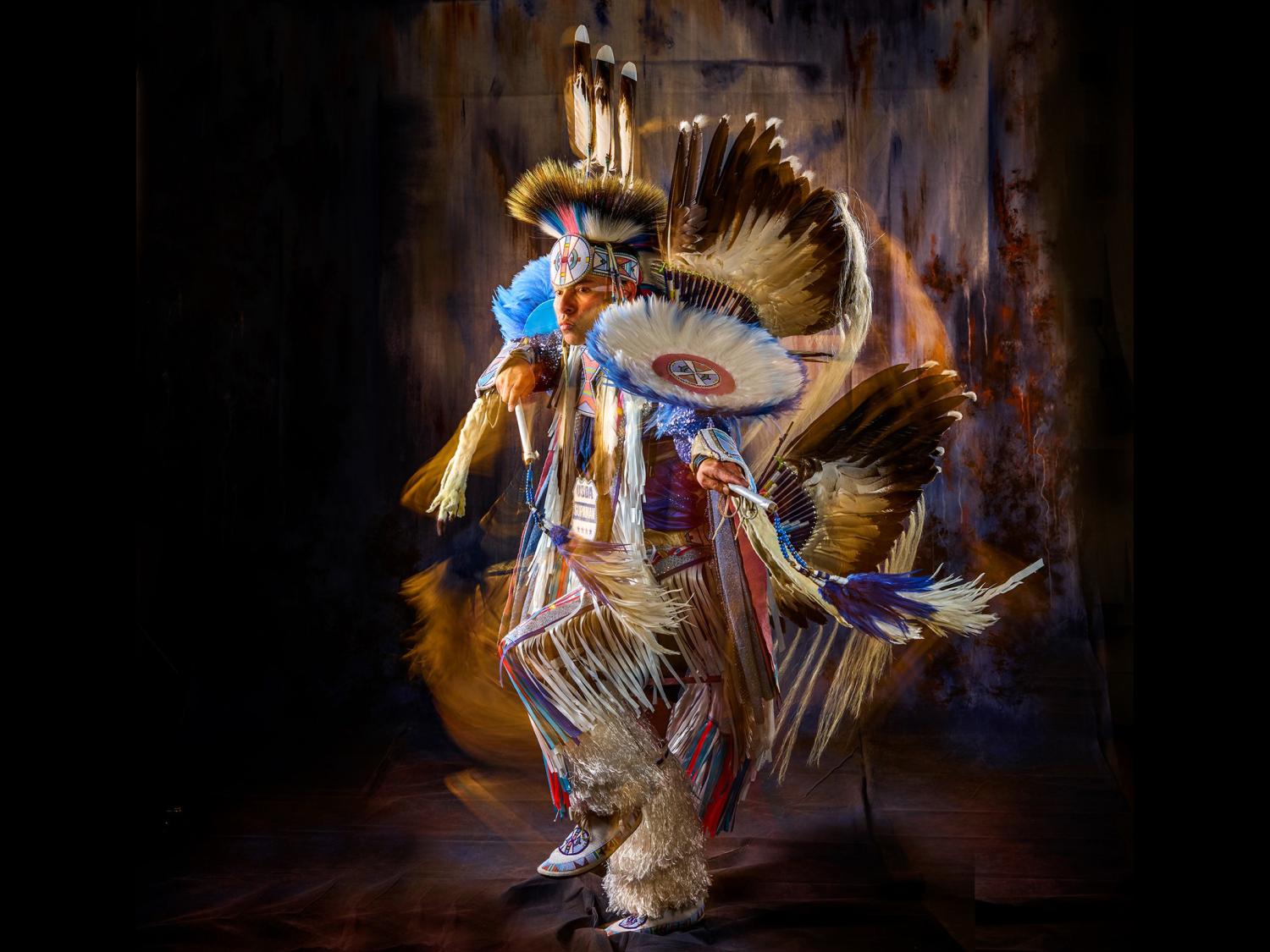 Supaman wearing beautiful traditional Native American clothing and dancing