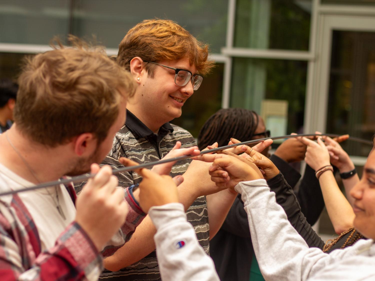 IDEA Ambassadors participate in a community building activity holding a bar in the air
