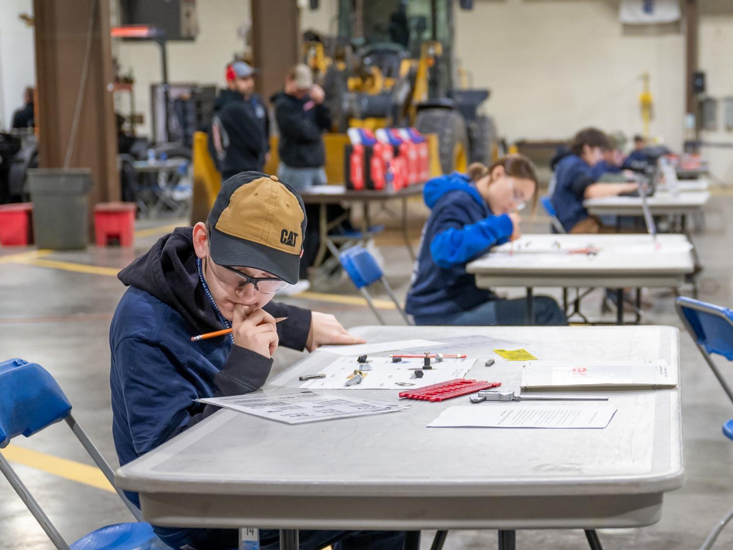 A young person sits at a table, thinking