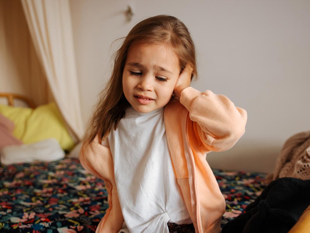 A young girl with an earache holds her ear.