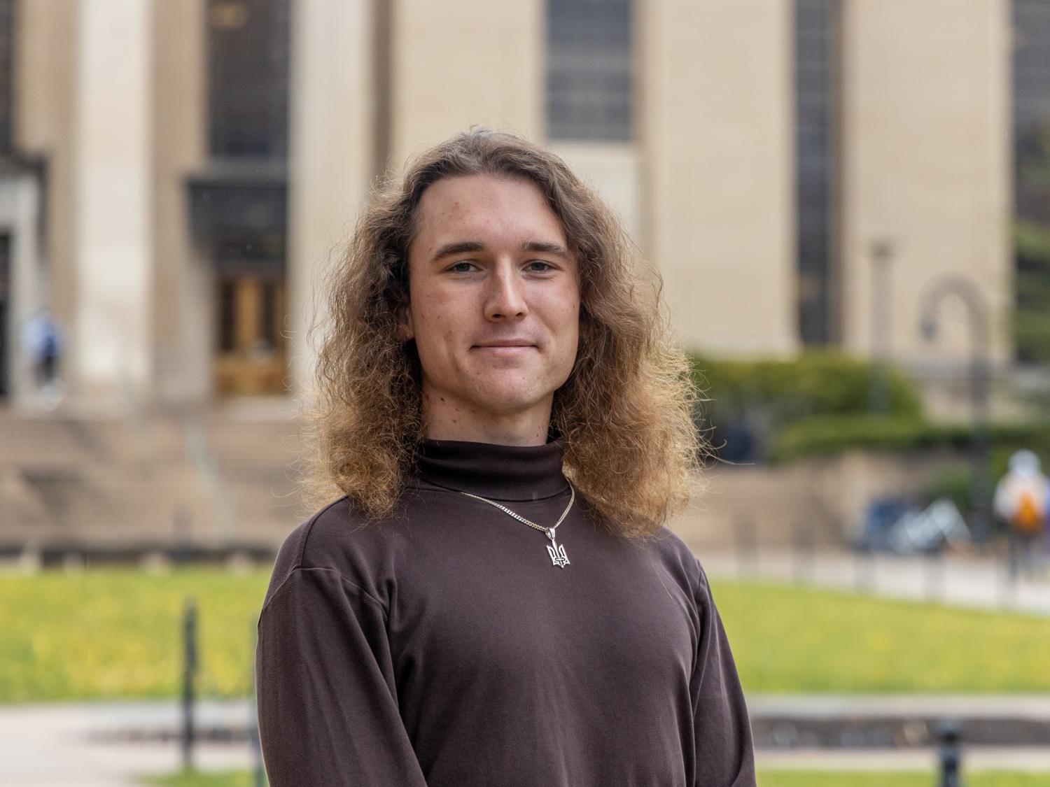 Igor Latsanych stands on Pattee Mall with Pattee Library and Paterno Library behind him.
