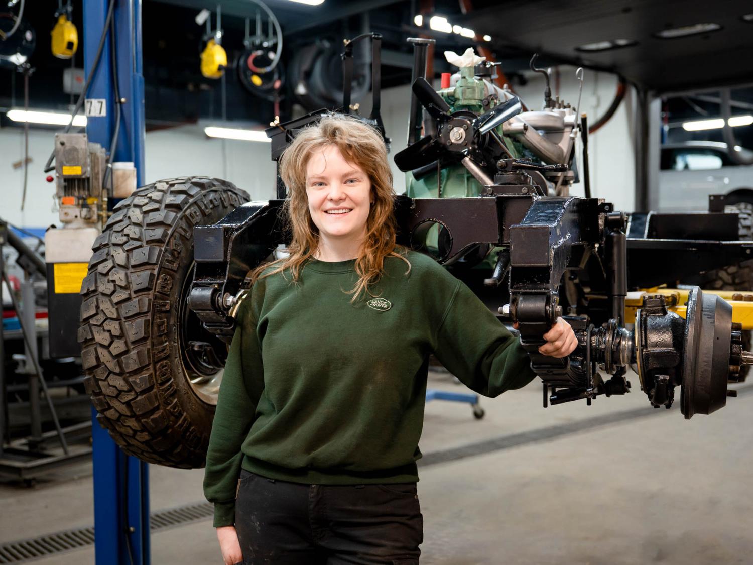 Sarah E. Crabtree stands in front of a bunch of car parts
