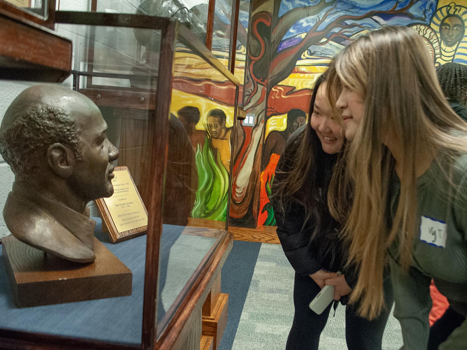 Students look at a bust of Oliver LaGrone in a case