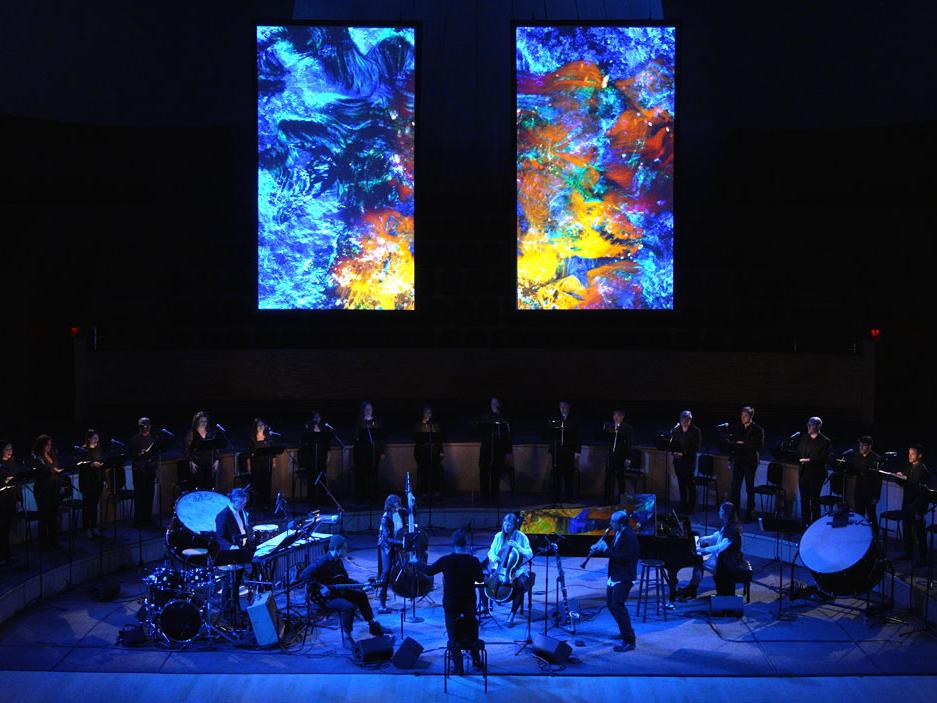 Large vertical video screens hang above a band and a choir.