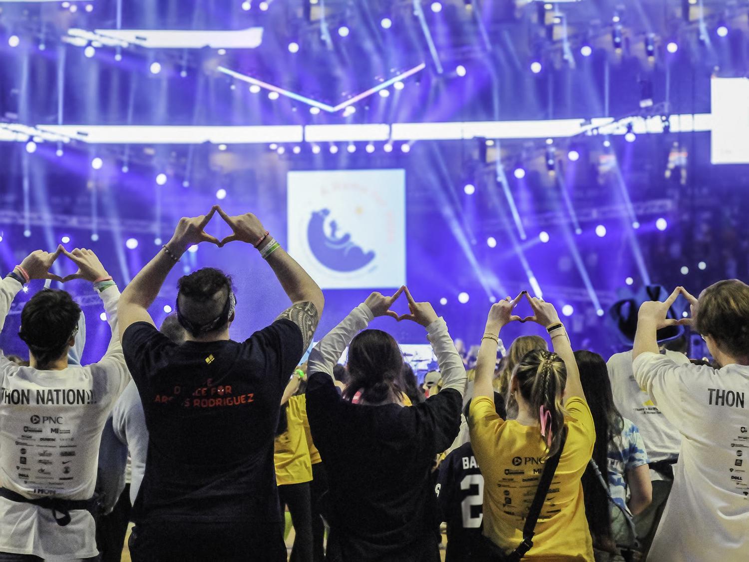 Scranton THON dancers face the stage and make the Four Diamonds symbol with their hands