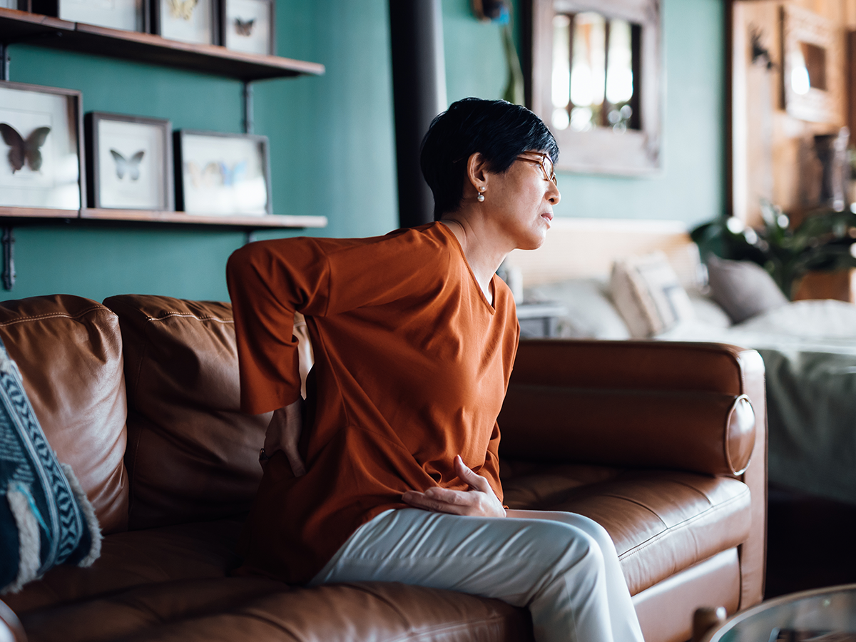 Person sitting on couch with a hand on their back