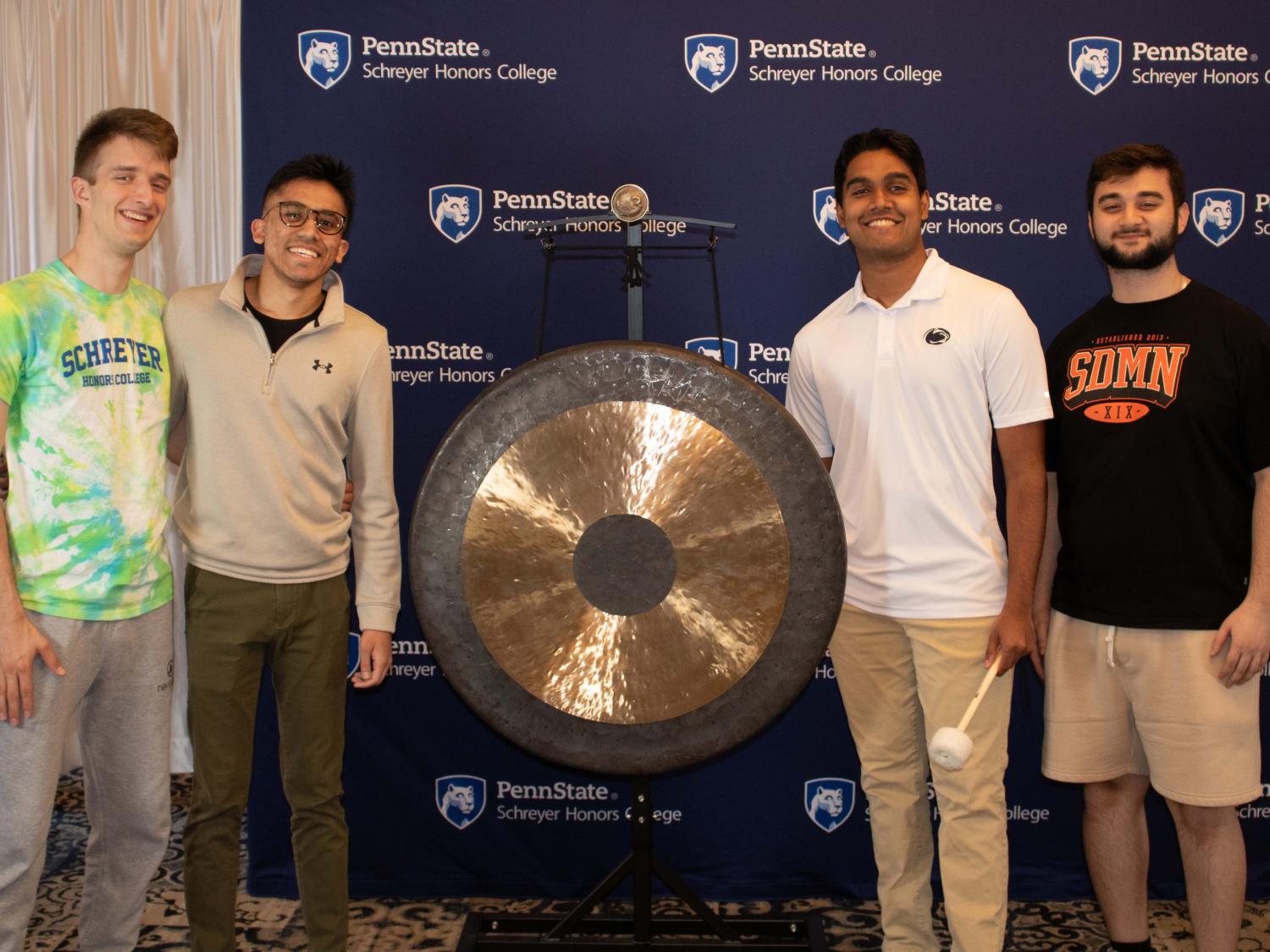 A group of 3 Schreyer Scholars pose with the gong