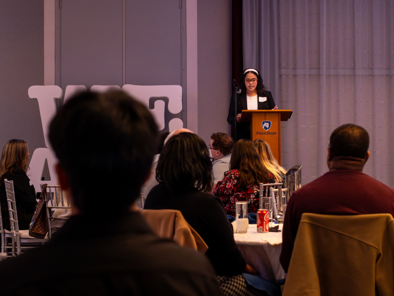 a female student speaks at a podium in a conference center 