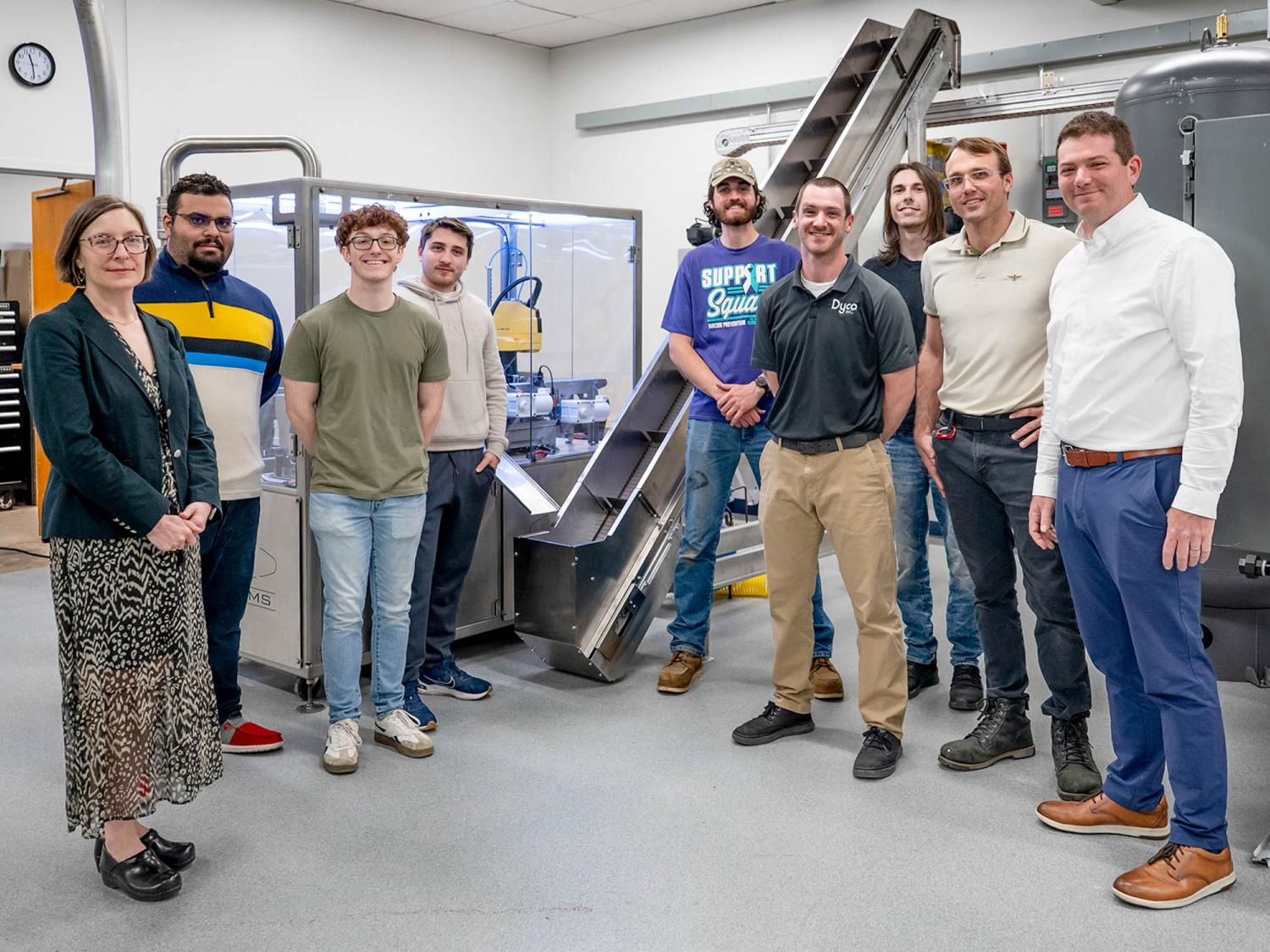 A group of people stand in front of a 9-foot incline conveyor