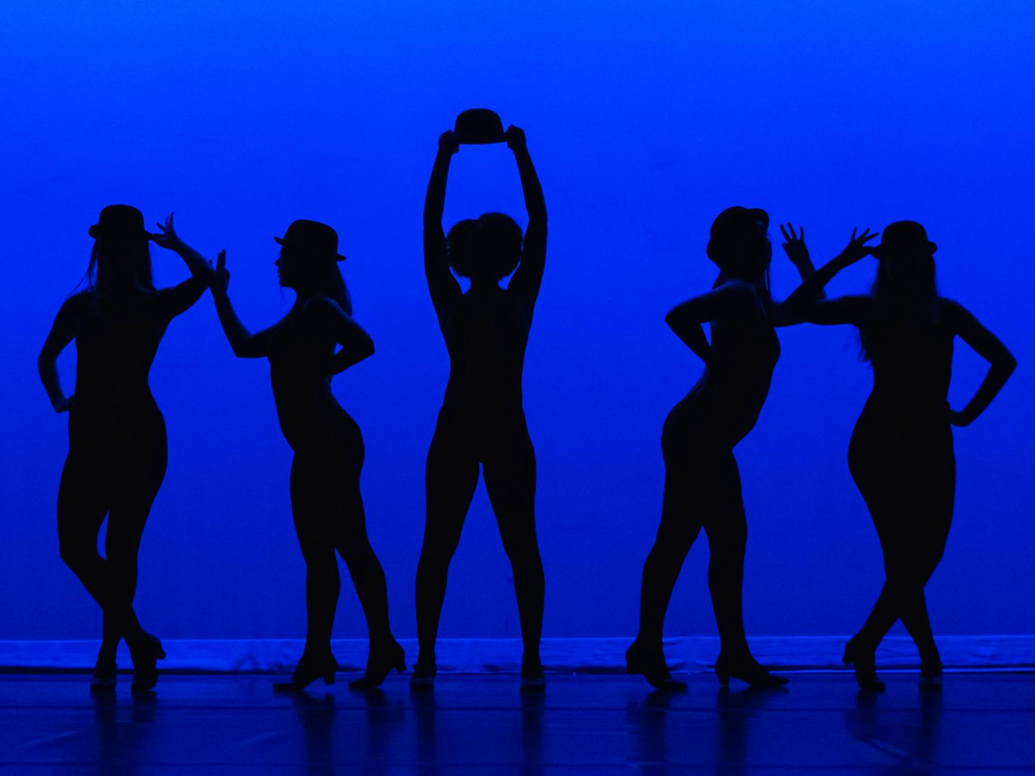 Penn State Altoona students do a jazz dance in front of a blue background