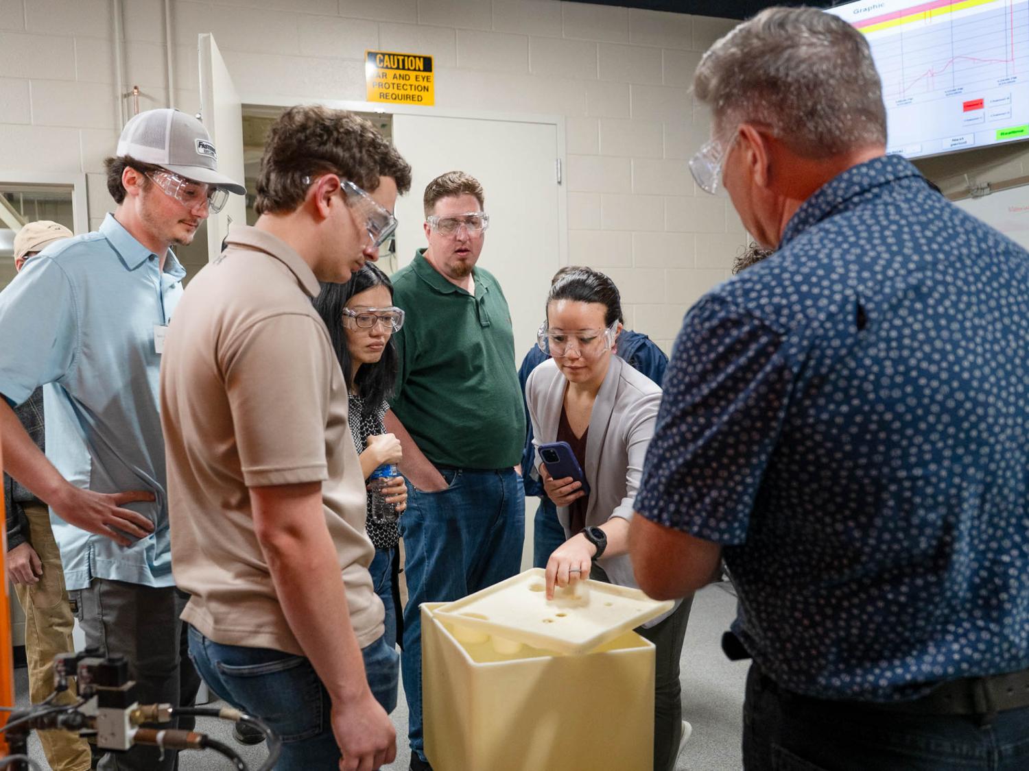 A group of people gathered around a project on a table