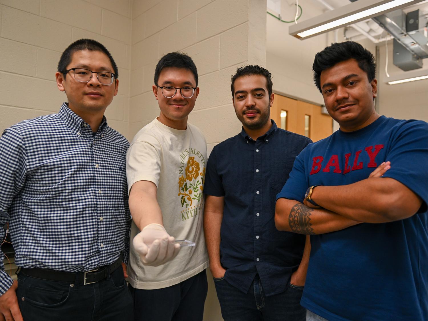 Four people pose for a photo with the second person holding a sample on a sample box 