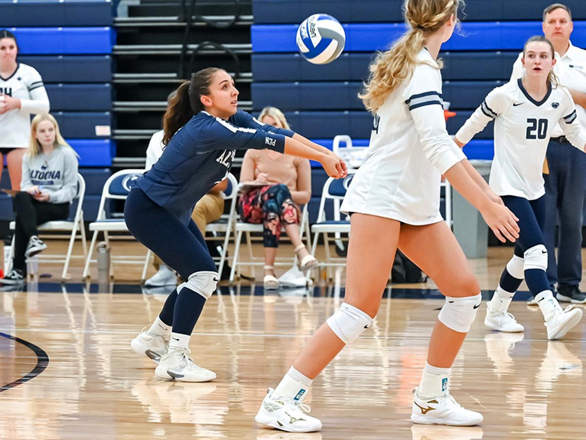 Penn State Altoona volleyball player Anna Batrus prepares to dig during a volleyball game, surrounded by teammates on the court.
