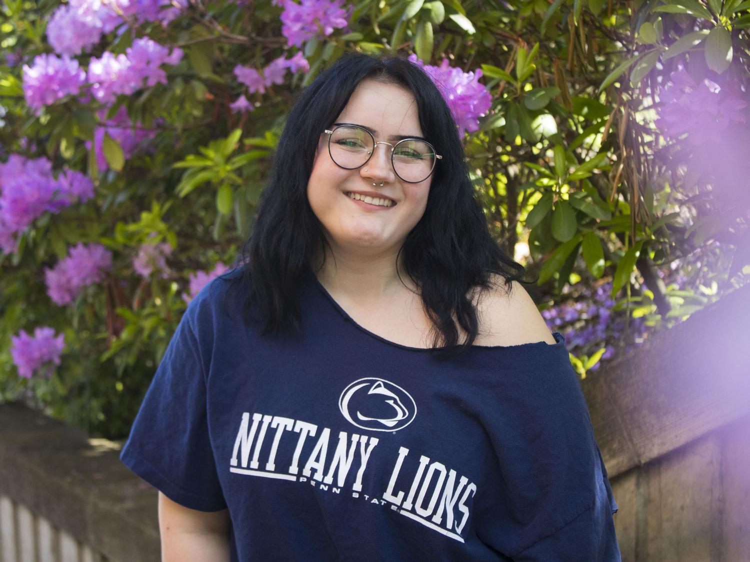 Student smiles in front of flowers