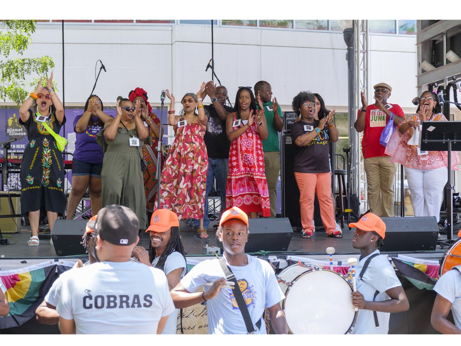 A group of people dancing joyously on a covered stage