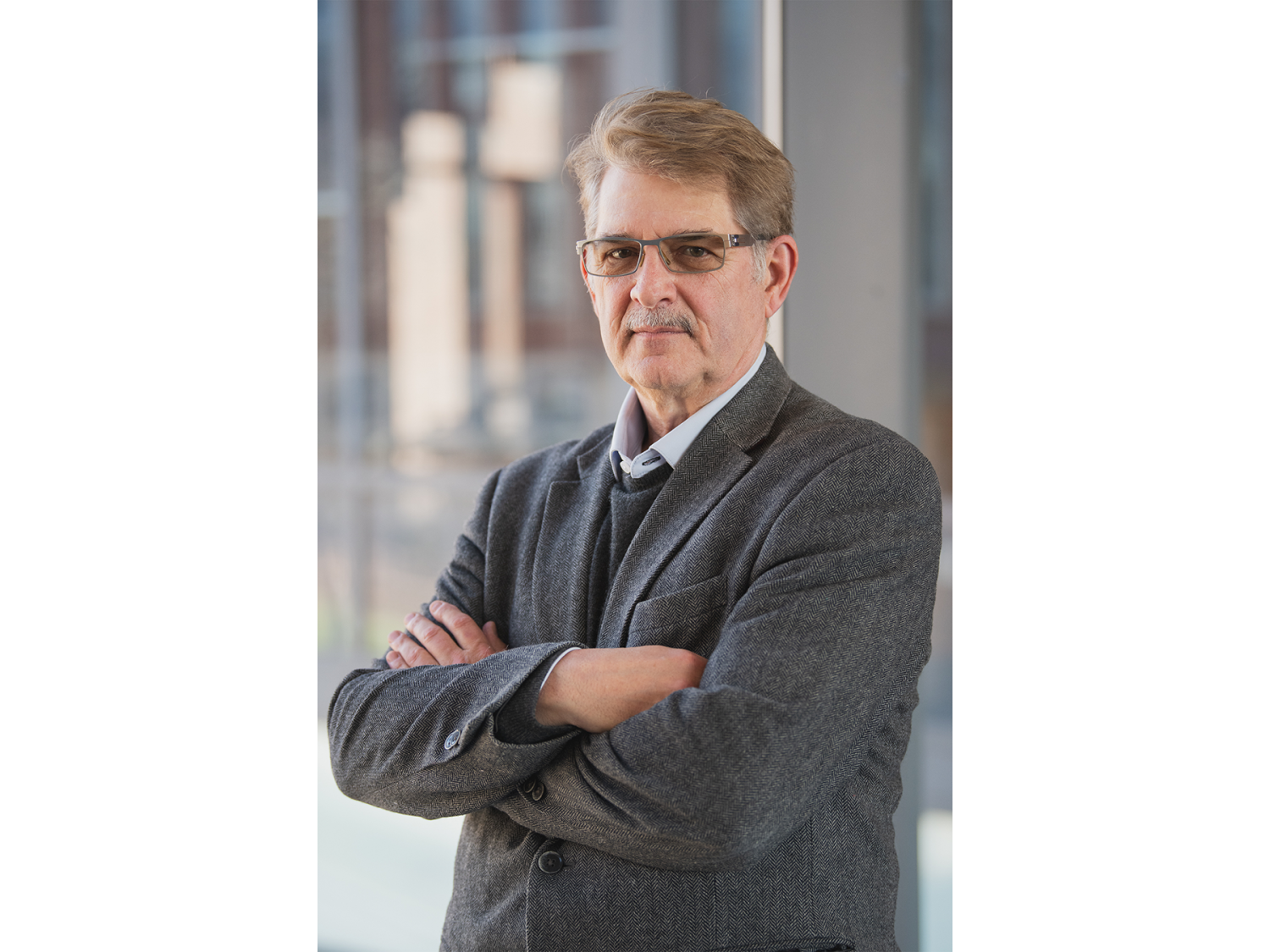 portrait of professor standing with arms crossed across his chest