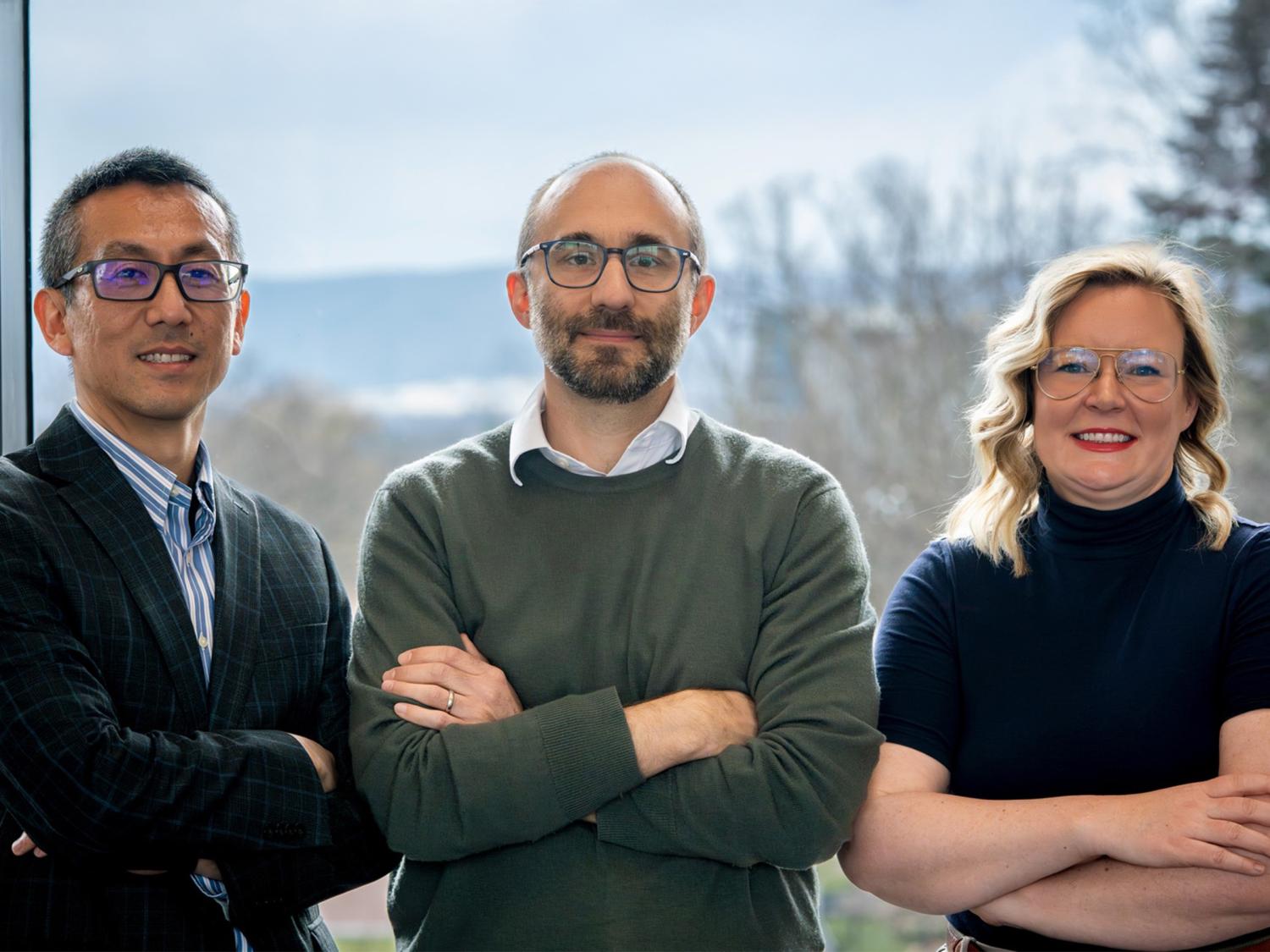 Three people crossing their arms pose for a photo. 