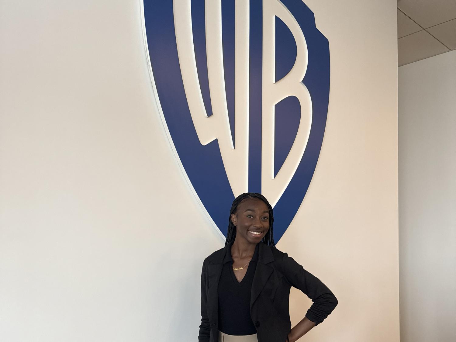 Danielle Sanois stands in front of the Warner Bros. logo. 