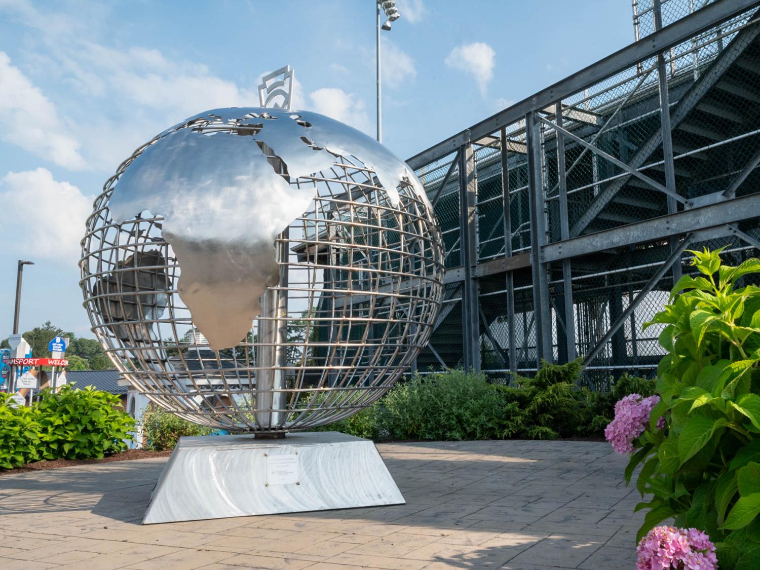 A large seven foot tall stainless steel globe rests on a stand outside a stadium