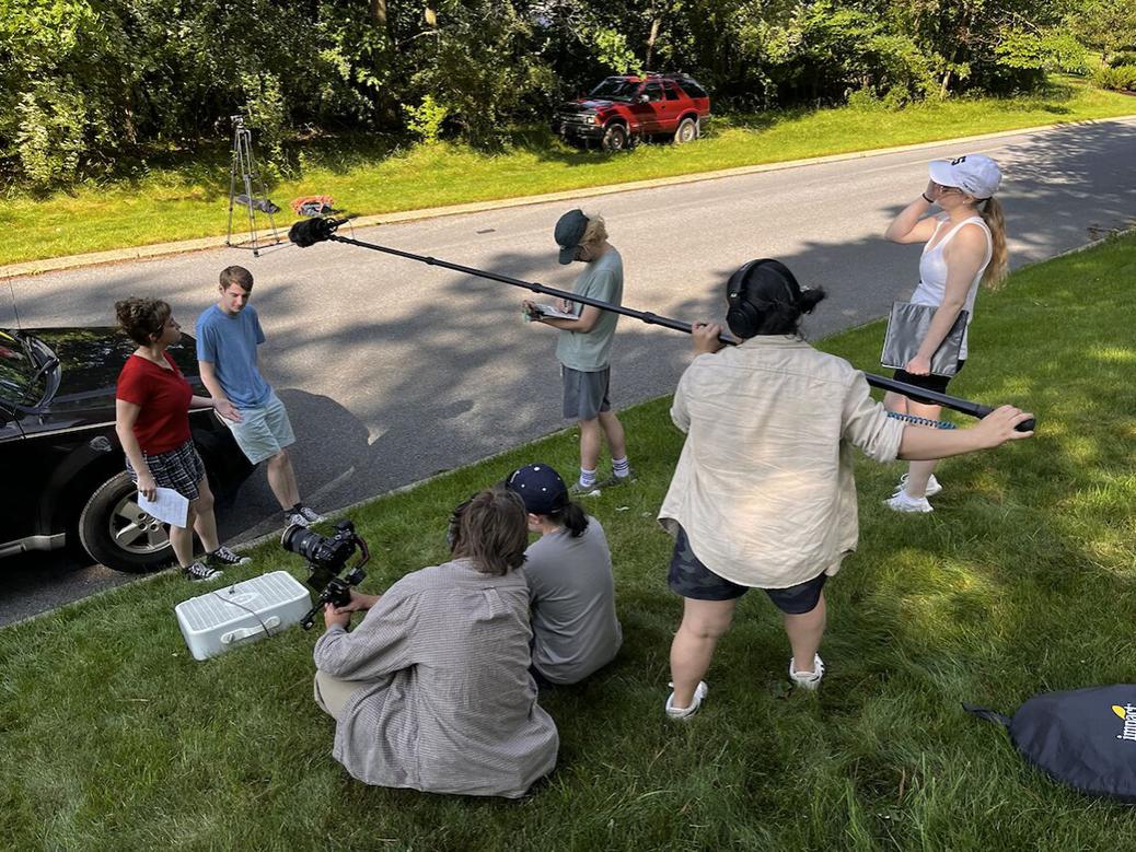 Two actors surround by a film and sound crew