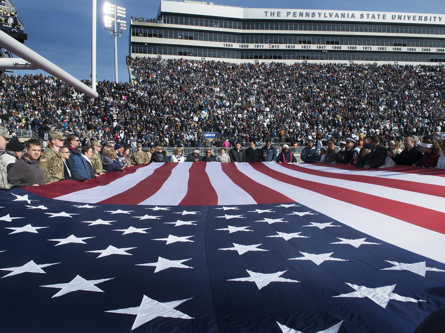 A giant American flag stretches across the end zone at Beaver Stadium.