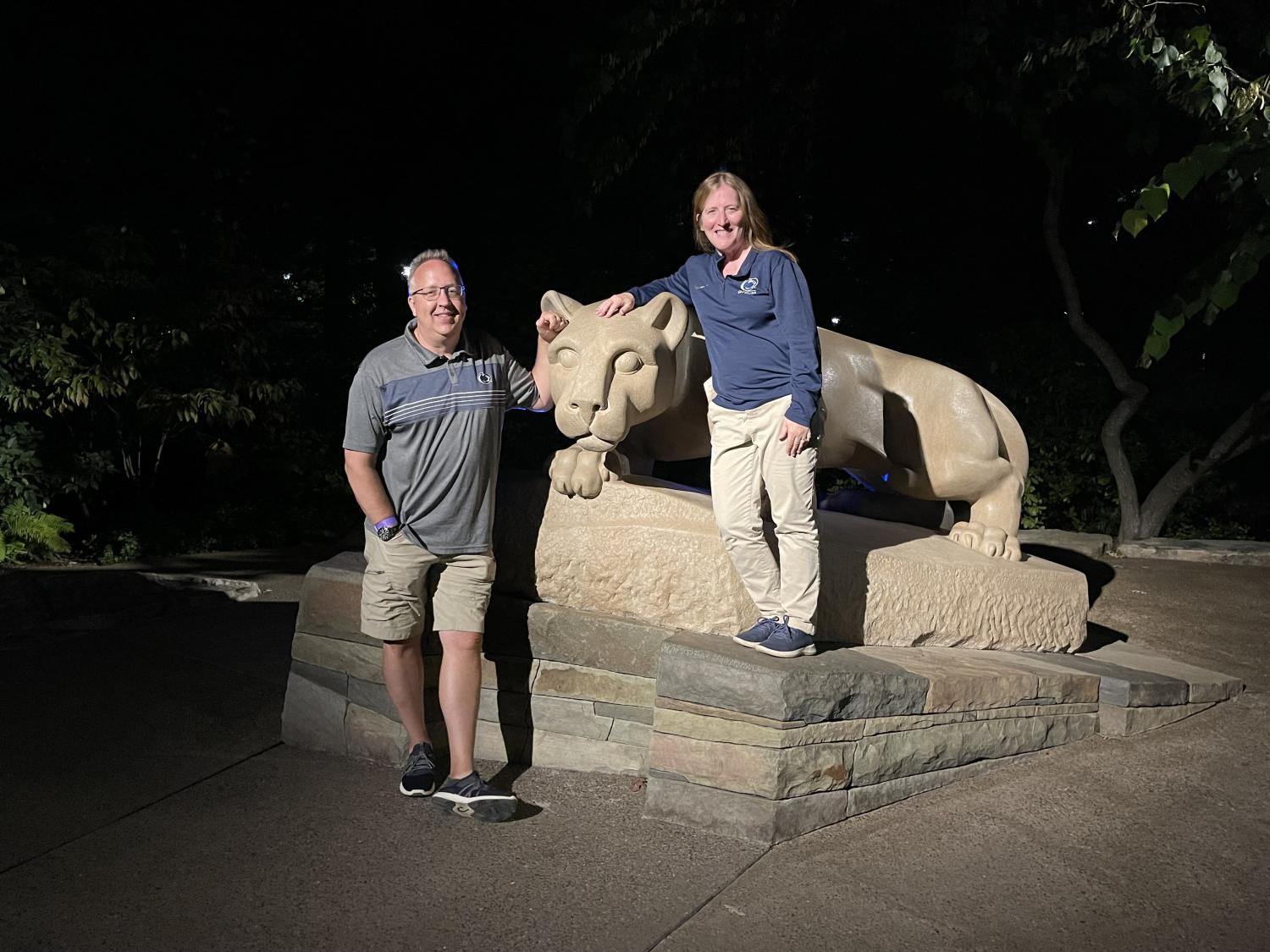 couple poses next to penn state lion statue at night