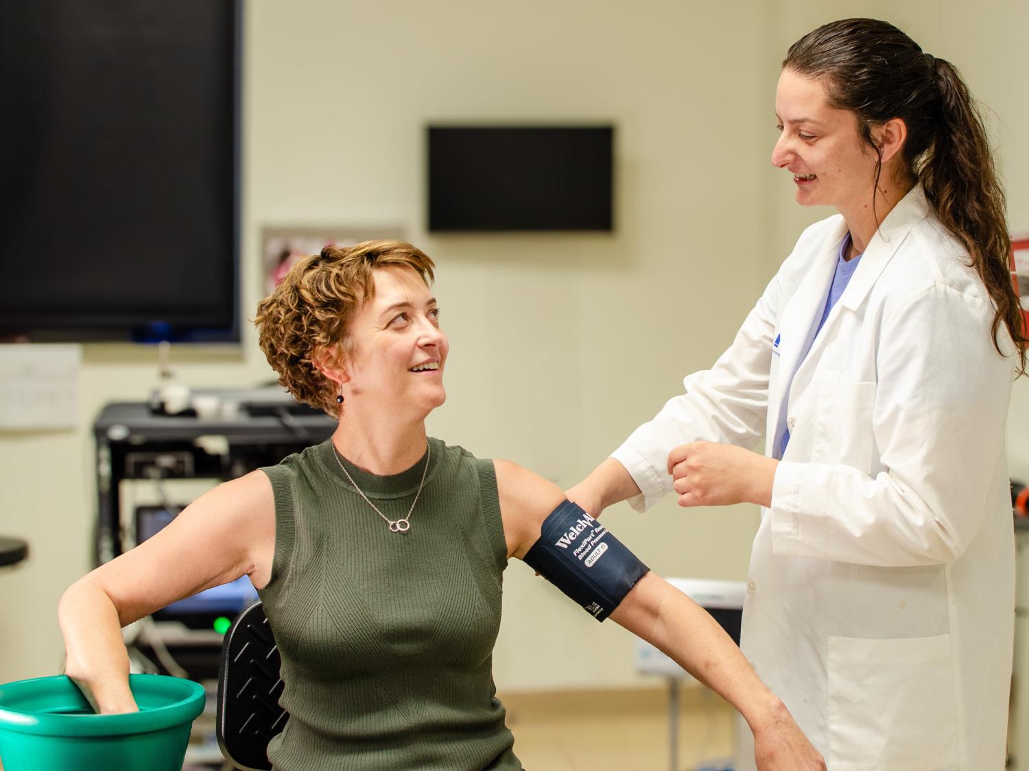 Lacy Alexander and Auni Williams pose in a lab to simulate a woman putting her hand in a bucket of water