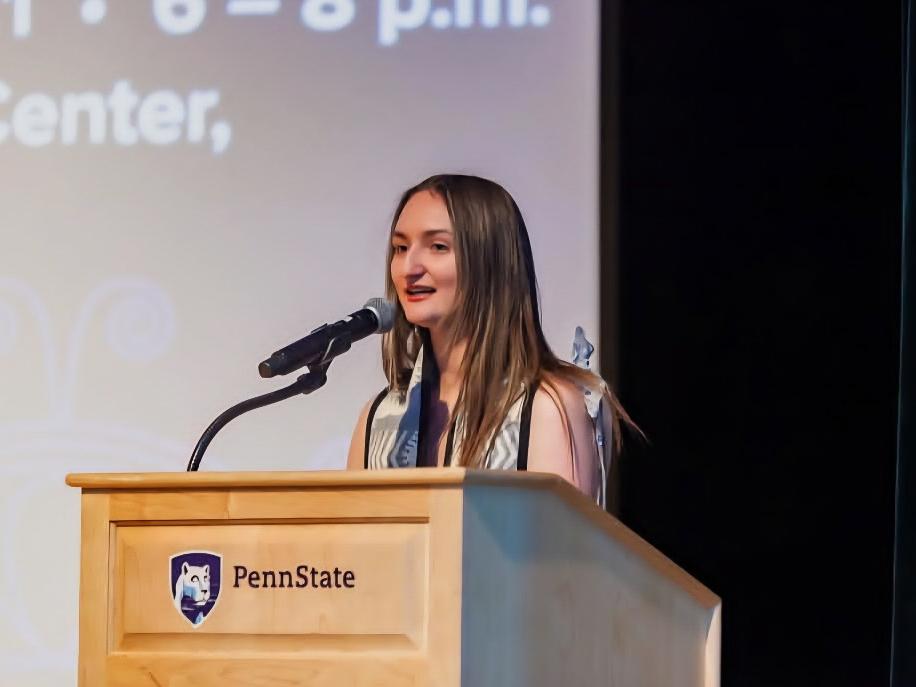 Kayla Cwalina giving a speech behind a Penn State podium.