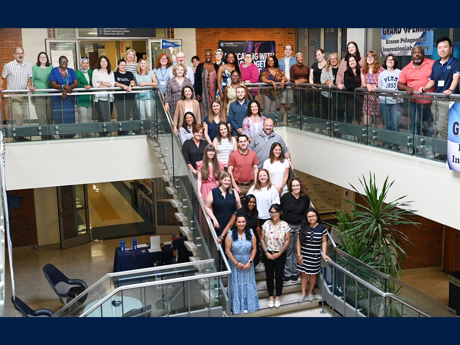 The Summer Summit attendees pose with faculty and staff for a group photo on and around a staircase.