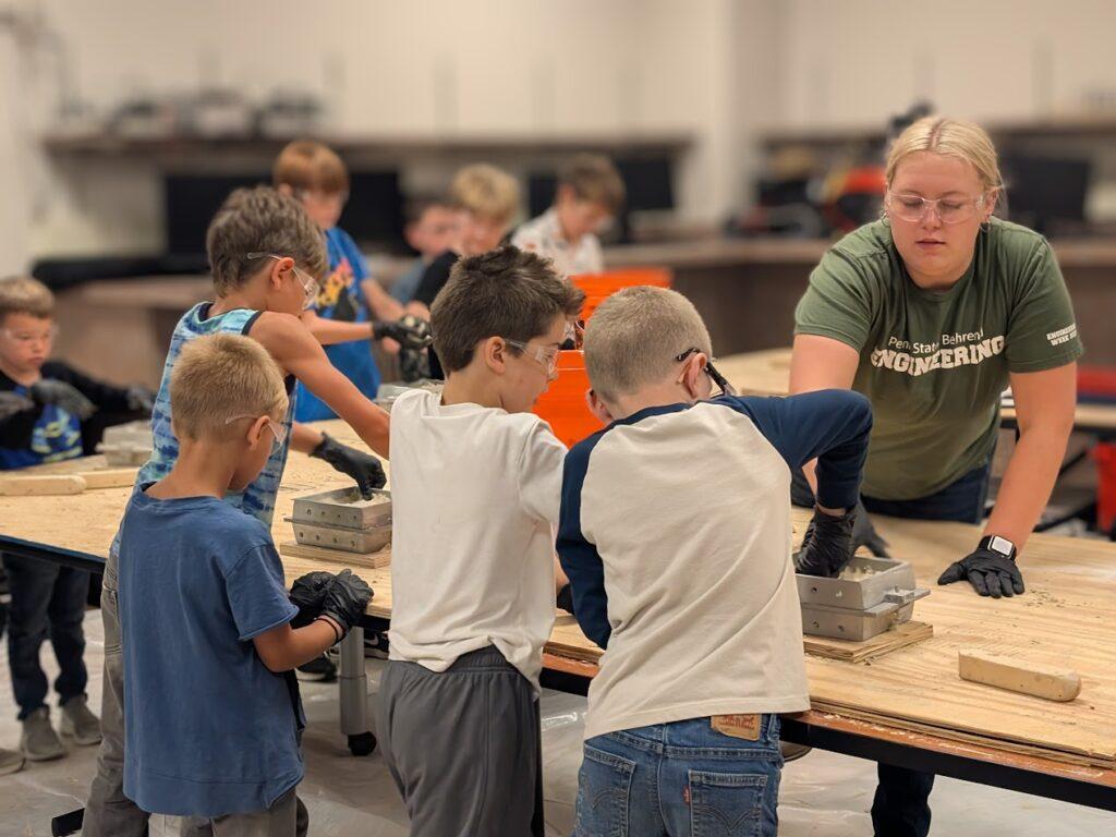 A group of pre-teens works with a mold in a metal-casting lab at Penn State Behrend.