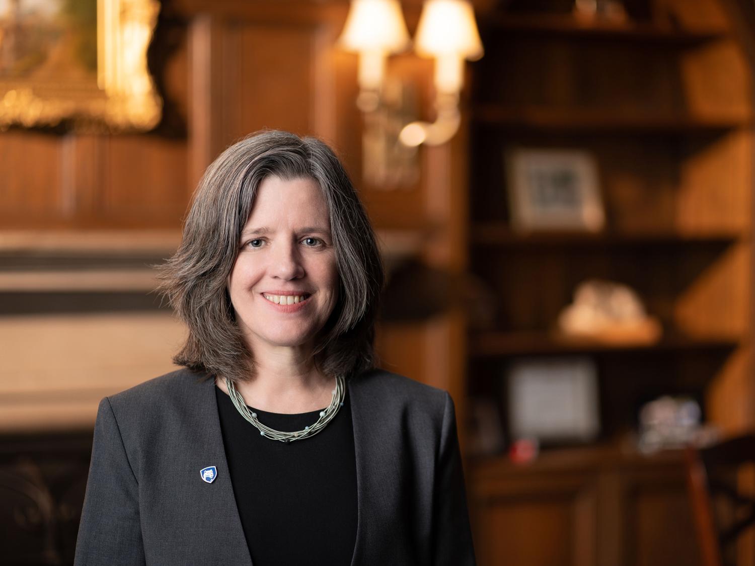 A headshot image of Liz Wright with a fireplace and shelves in the background