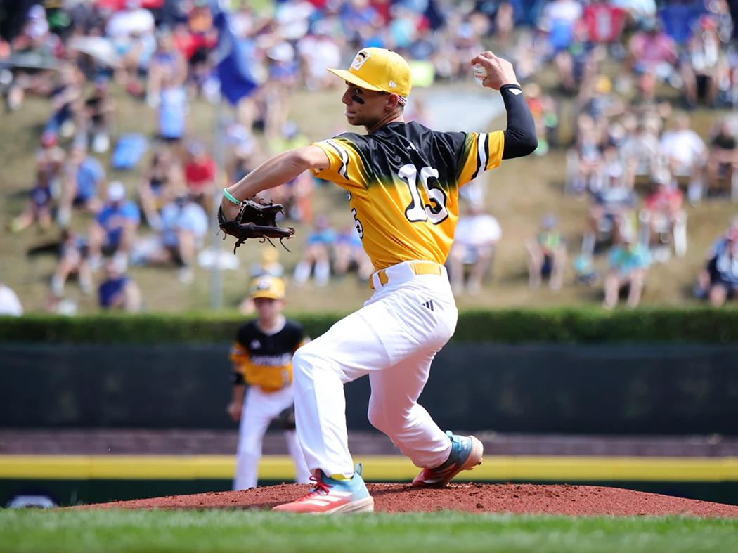 A baseball pitcher in a yellow uniform delivers a pitch
