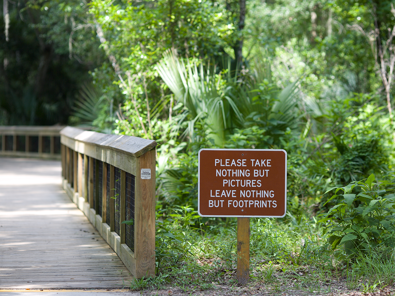 Sign next to a trail that reads, "please take nothing but pictures leave nothing but footprints."