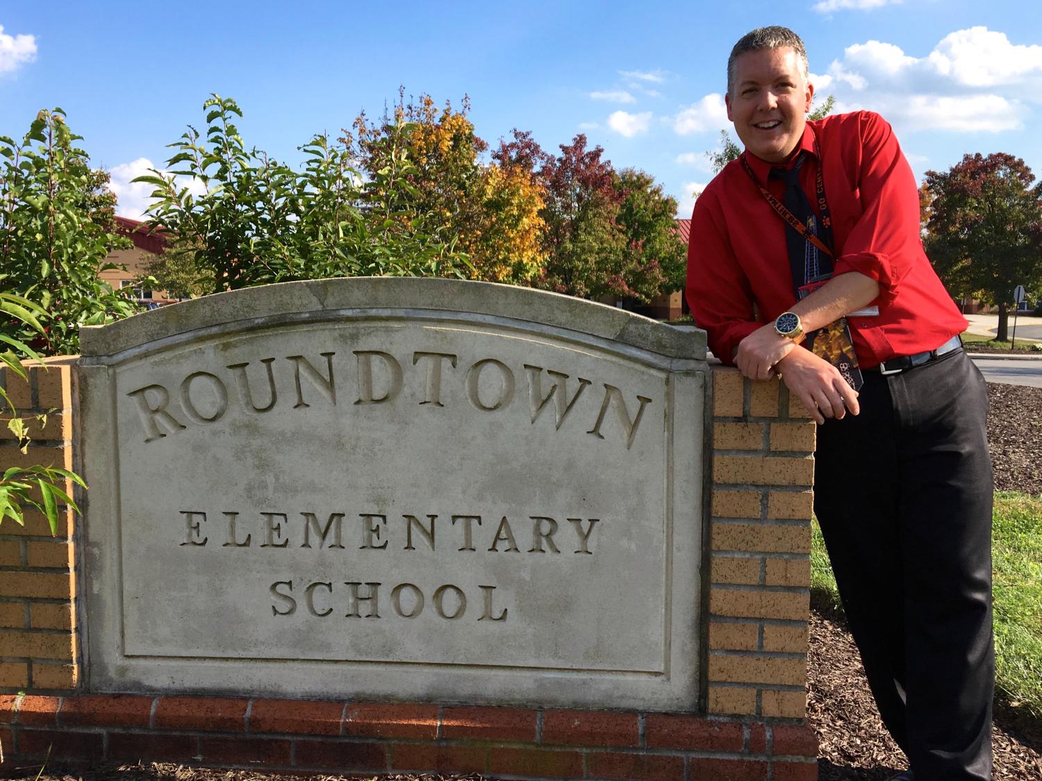 Man wearing red shirt leans against concrete sign