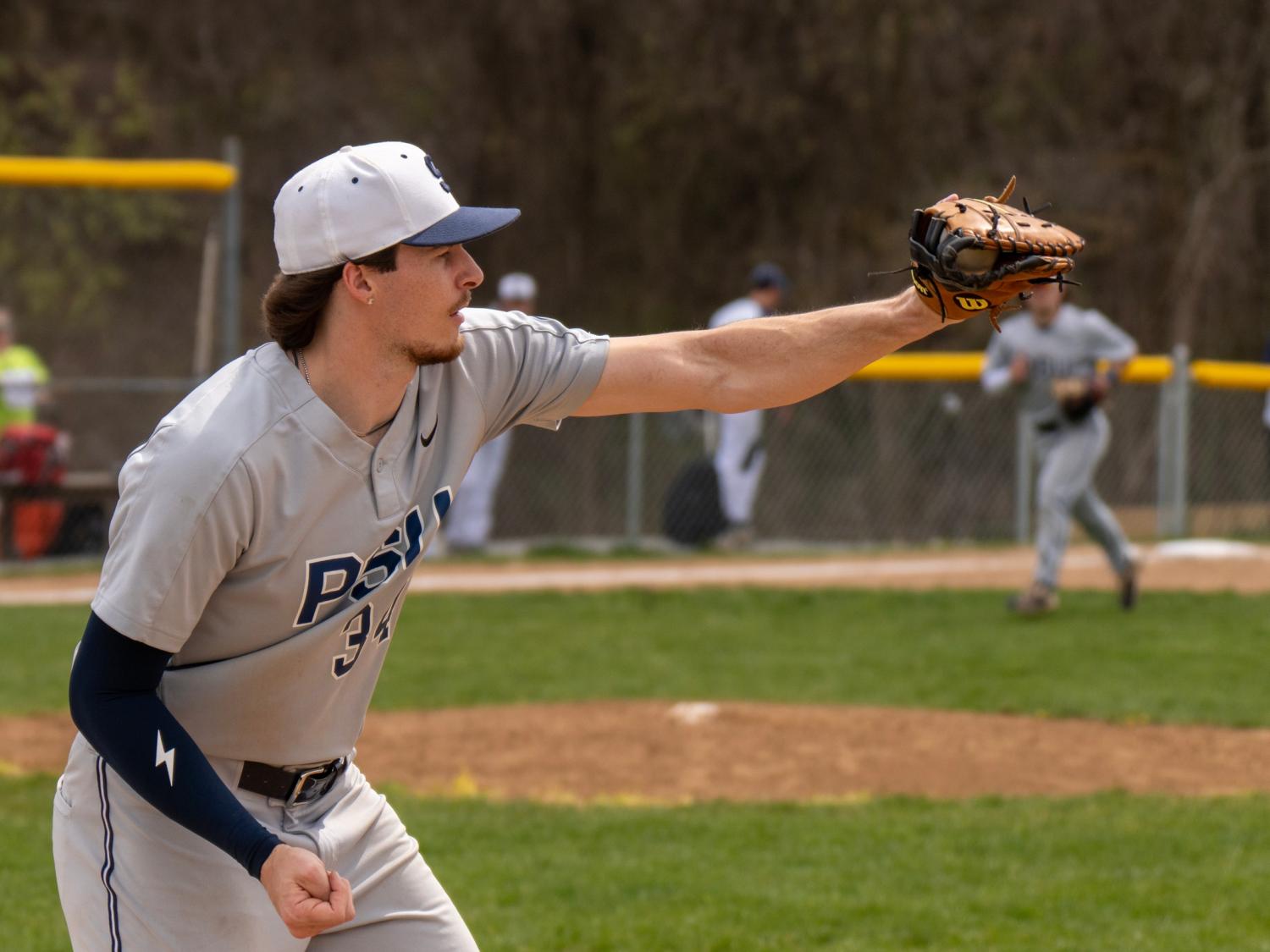 Penn State baseball player Brayden Patton, wearing a gray uniform and cap, pitches the ball during a game on a sunny afternoon.