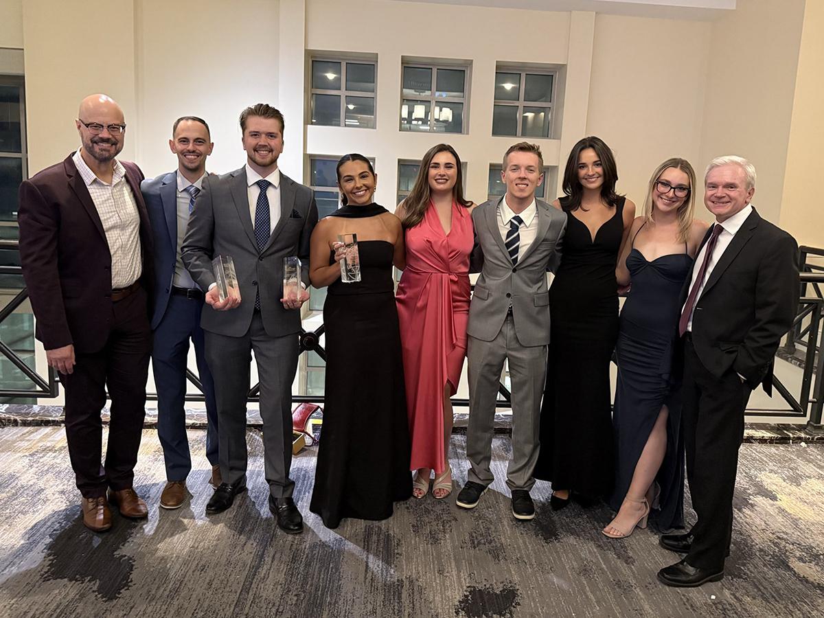 A group of well-dressed people posing for a photo while holding some awards.