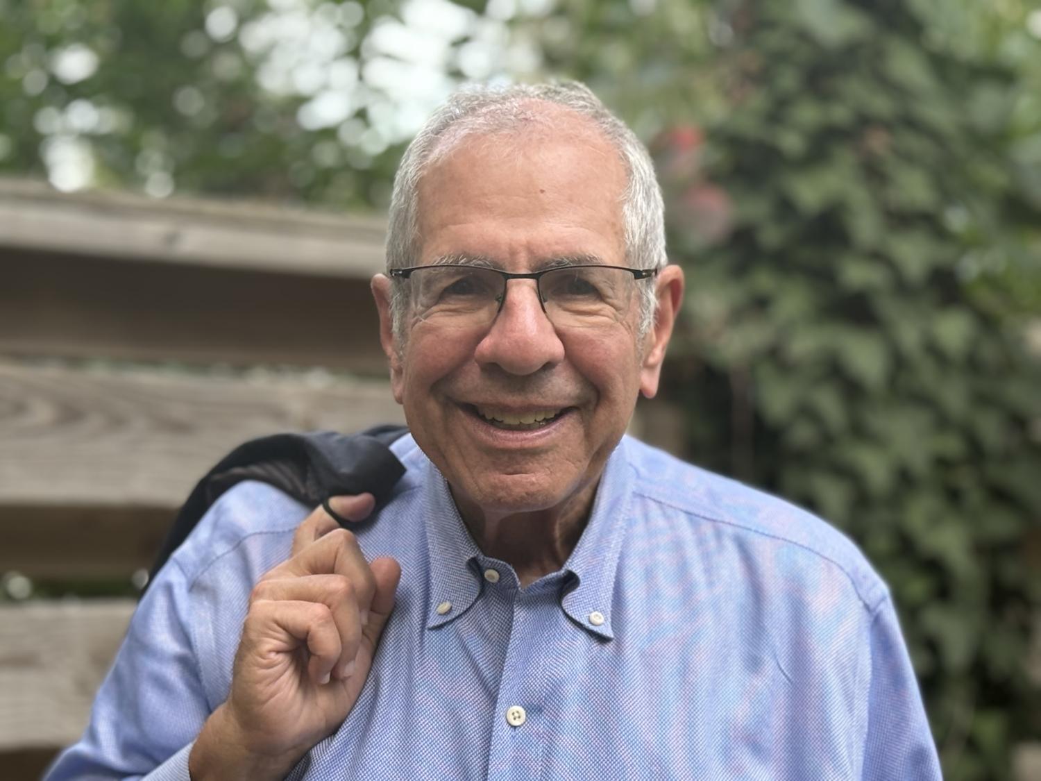 headshot of Elliott Weinstein standing outside near a fence and trees
