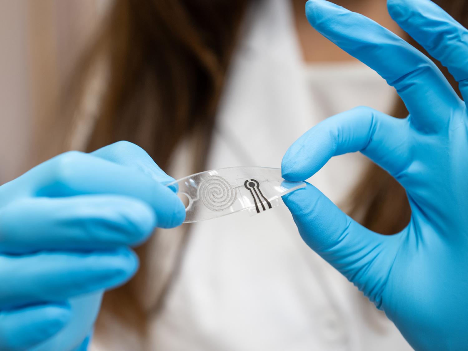 Hands in blue gloves holding a flexible sensor