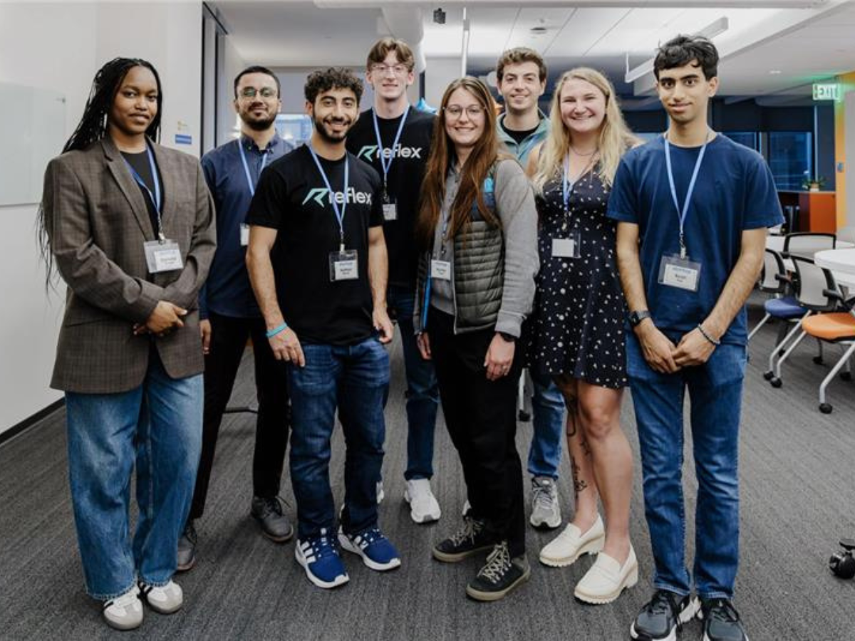 A group of eight students stand together posing for a photo