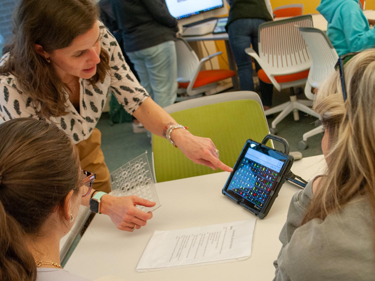 A professor points to icons on the screen of an alternative and augmentative communication device