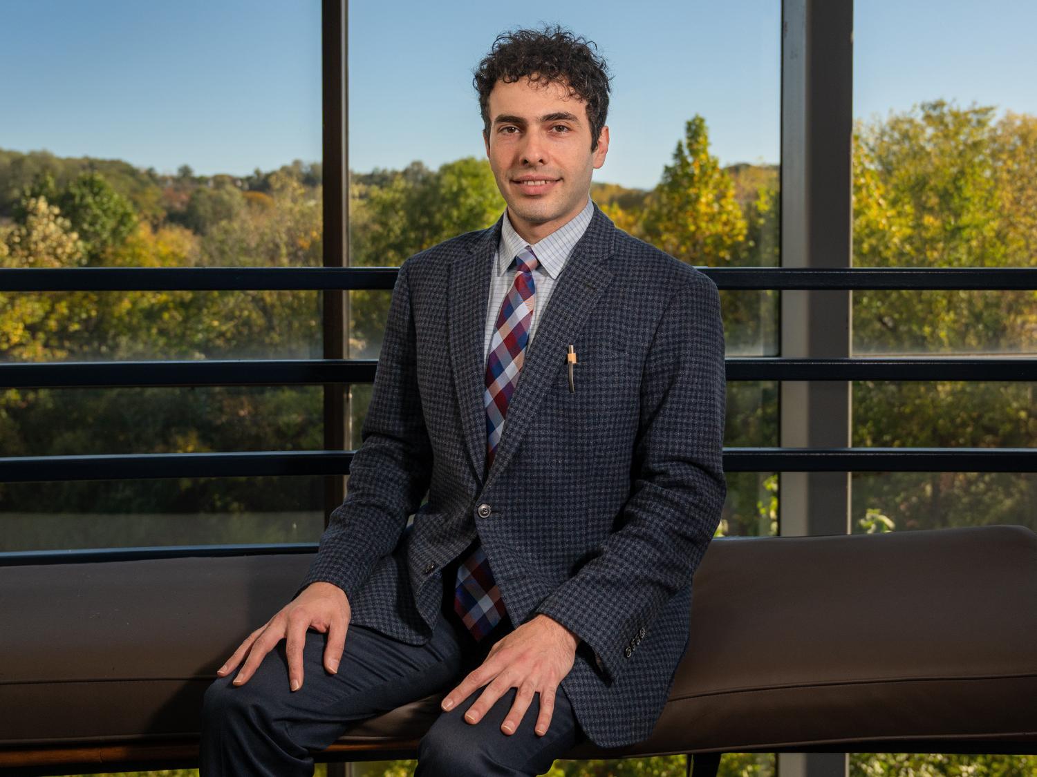 Engineering management associate professor Ashkan Negahban sits in front of a view overlooking trees on Penn State Great Valley's campus