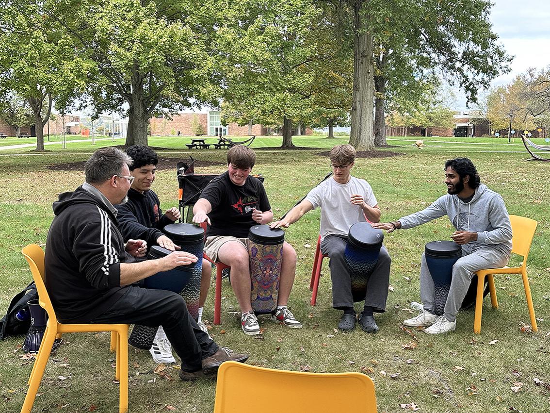 A group of people sit in a circle with drums.