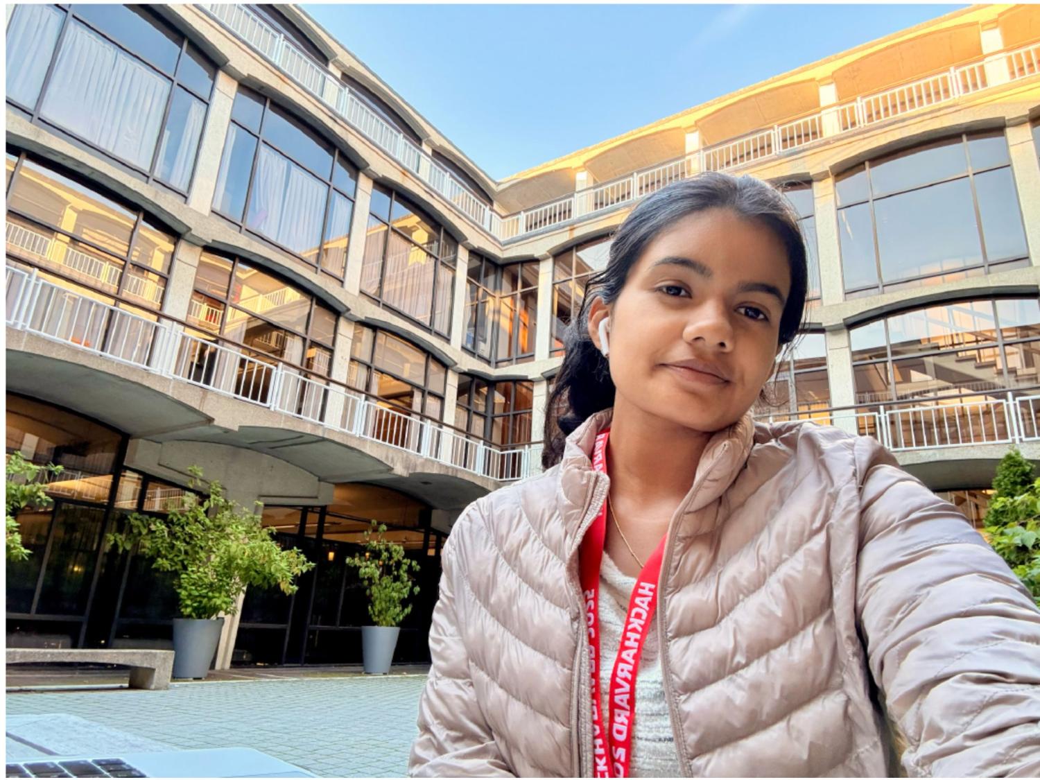 dark-haired student in winter coat in front of college building