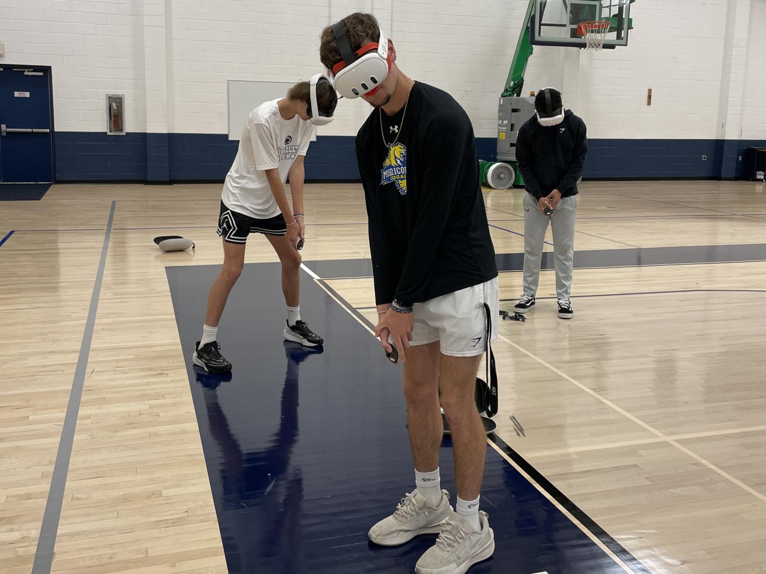 Three students wearing virtual reality headsets in gymnasium