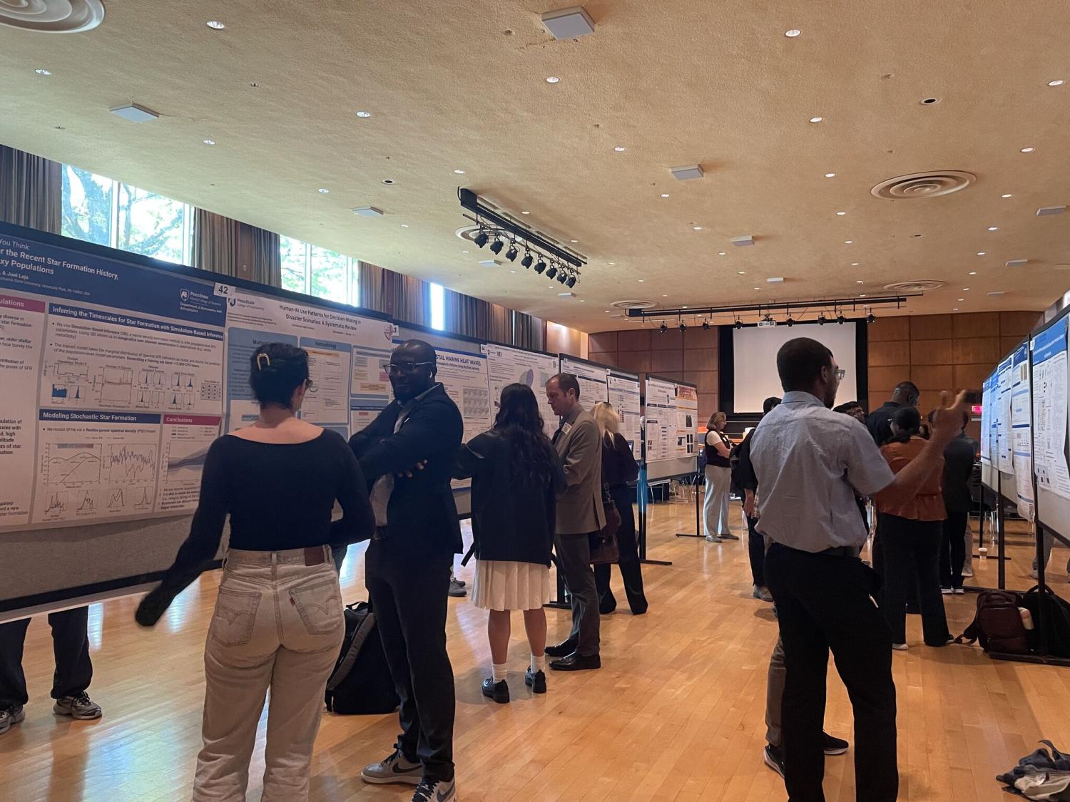Students stand at their research posters with symposium attendees.