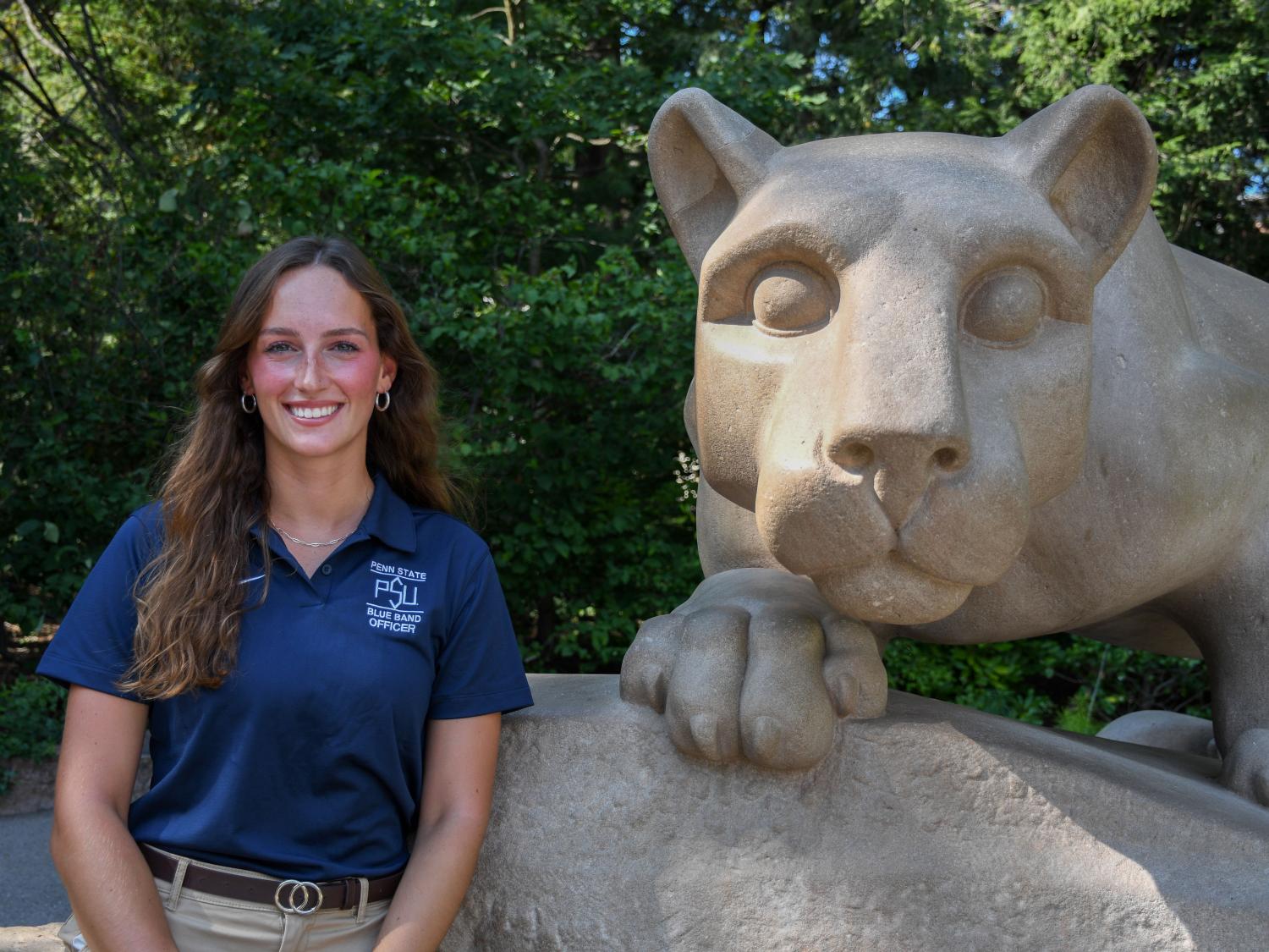 Lucy Schilling stands next to the Nittany Lion Shrine wearing her Blue Band officer shirt.